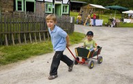 Ein Junge zieht einen Bollerwagen, in dem ein kleinerer Junge sitzt