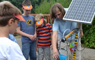 Kinder erhalten an einem Solarmodul Informationen zum Thema Strom