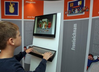 Ein Junge nutzt in der Ausstellung Himmelfahrt und Aschenkreuz den PC, um sich zu informieren