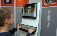 Ein Junge nutzt in der Ausstellung Himmelfahrt und Aschenkreuz den PC, um sich zu informieren