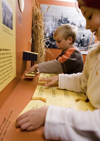 Kinder arbeiten in der Ausstellung 'Stroh' mit den Texttafeln