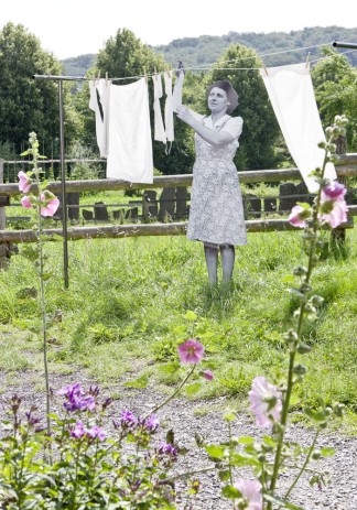 Eine nachgestellte Szene mit Pappfigur: Wäsche wird an der Wäscheleine im Garten aufgehangen