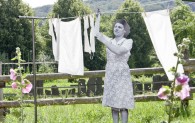 Eine nachgestellte Szene mit Pappfigur: Wäsche wird an der Wäscheleine im Garten aufgehangen