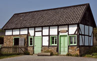 Das Gebäude der Feilenhauerei mit sichtbarem Fachwerk und hellgrünen Türen beherbergt zur Zeit die Sattlerei und einen Ziegenstall.