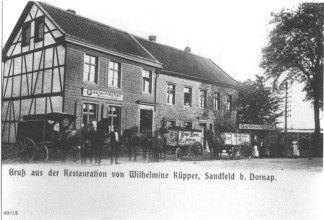 Eine historische Postkarte in schwarz-weiß zeigt die Gaststätte Römer. Auf der Straße stehen drei Pferdefuhrwerke und Personen in zeitgenössischer Kleidung
