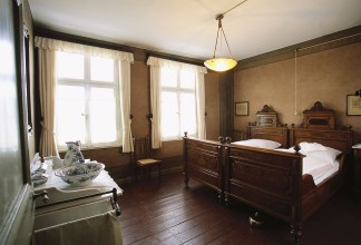 Blick in das Elternschlafzimmer im ersten Obergeschoss. Die Einrichtung mit edlen Hölzern lässt den Wohlstand der Familie erkennen.