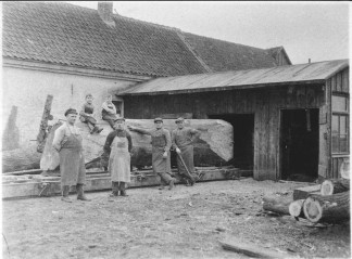 Eine historische Aufnahme in schwarz-weiß: Arbeiter posieren vor dem Sägegatter am Originalstandort