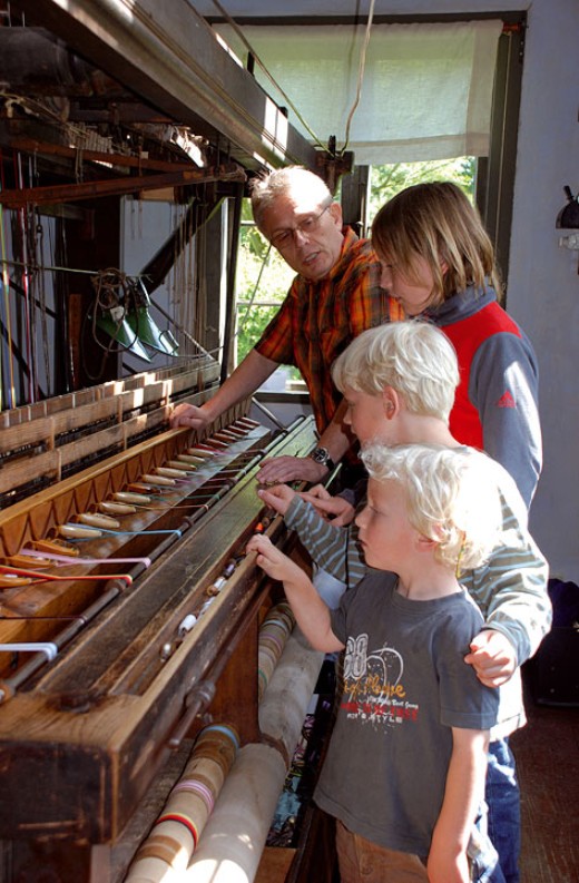 Der Bandweber erklärt Kindern den historischen Bandwebstuhl