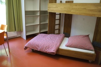 Ein Pflegebett, das auf Rollen gelagert ist, ist unter einem Etagenbett hervor gezogen