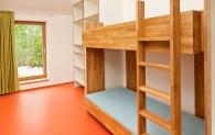 Blick in ein Zimmer der Museumsherberge, Etagenbett aus Holz mit orangefarbigem Fußboden