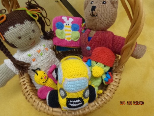 Korb mit gehäkeltem Spielzeug. Vom Teddybär über die Puppe bis hin zum Auto.