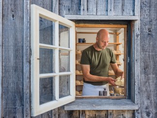 Durch ein geöffnetes Fenster des historischen Backes ist der Museumsbäcker bei der Arbeit mit dem Teig zu sehen.