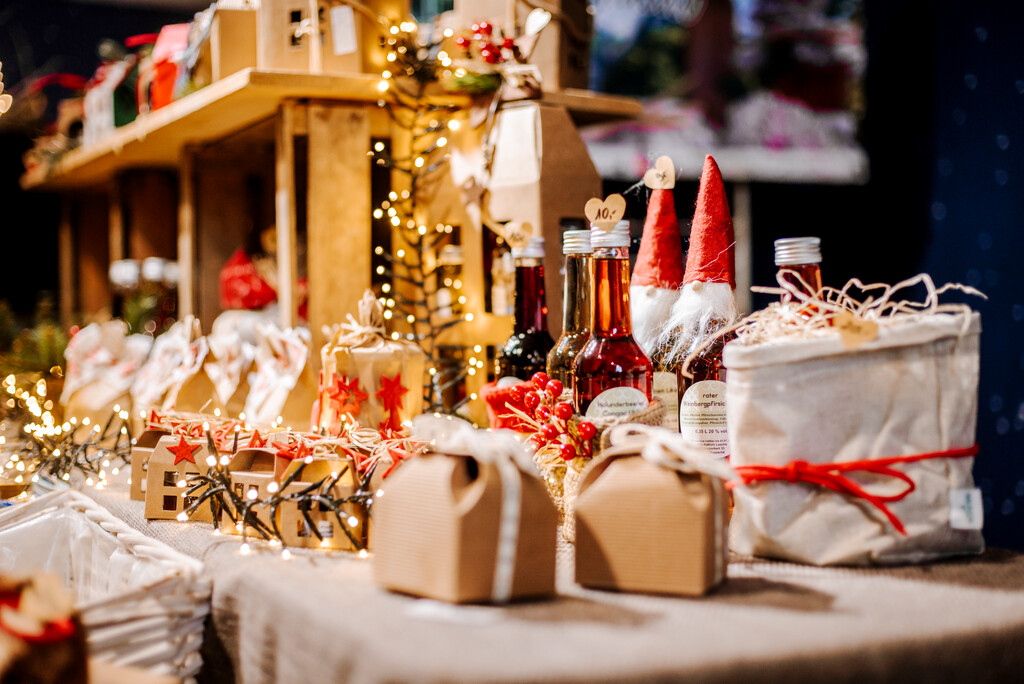 Viele verschiedene weihnachtliche dekorierte und regionale Waren werden auf einem Tisch präsentiert. Dazwischen liegen Lichterketten.