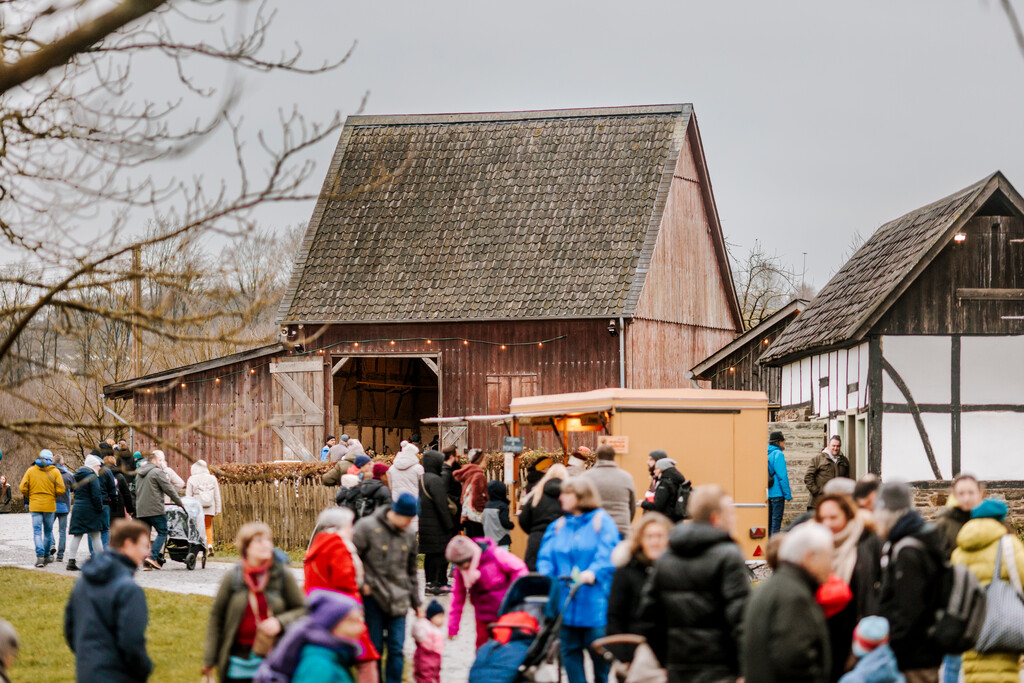 Viele Besuchende tummeln sich auf dem Museumsgelände. Im Hintergrund ein Verkaufsstand, eine Scheune und ein kleines historisches Fachwerkhaus.