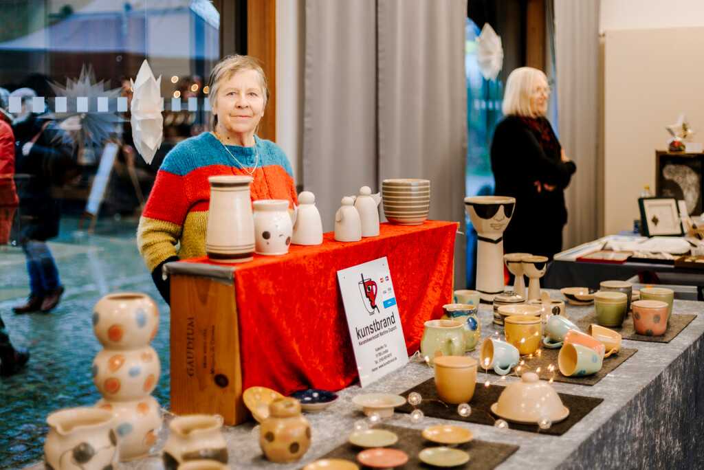 Zwei Frauen präsentieren ihre Waren an Ständen in der Museumsherberge. Im Vordergrund wird Keramik angeboten.