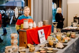 Zwei Frauen präsentieren ihre Waren an Ständen in der Museumsherberge. Im Vordergrund wird Keramik angeboten.