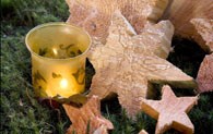 Adventliche Dekoration: Holzsterne und ein gelbes Windlicht mit brennender Kerze